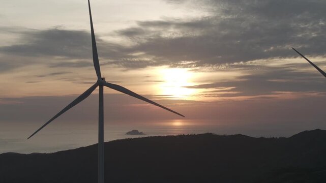 Aerial drone footage of sunrise over Ky Mountain Wind Farm near Quy Nhon, Gia Lai, Vietnam, featuring coastal scenery, wind turbines, golden morning light and renewable energy.