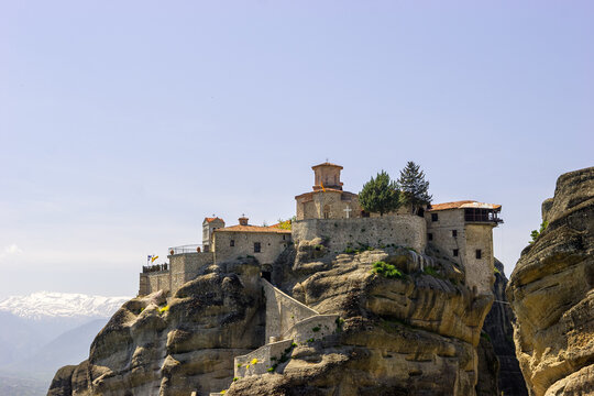 The Holy Monastery of Great Meteoron perched atop a rock formation in Meteora, Greece, under a clear blue sky.