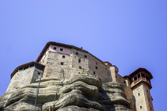 The Monastery of Great Meteoron, perched atop a rock formation in Meteora, Greece, under a clear blue sky.