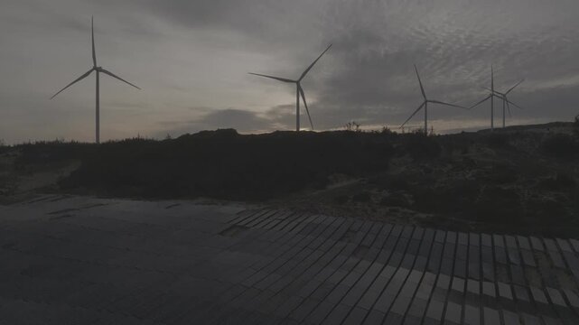 Aerial drone footage of sunrise over Ky Mountain Wind Farm near Quy Nhon, Gia Lai, Vietnam, featuring coastal scenery, wind turbines, golden morning light and renewable energy.