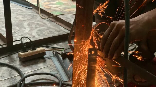 Close-up 4K footage of an angle grinder cutting a steel frame during metal fabrication. Bright flying sparks highlight industrial craftsmanship, engineering, construction, and manufacturing work.