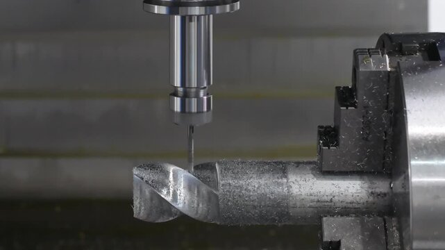 Close-up of precision metalworking machine. Cylindrical metal workpiece rotates inside  machine. Tool bit hovers above workpiece for machining. tech industrial technology background