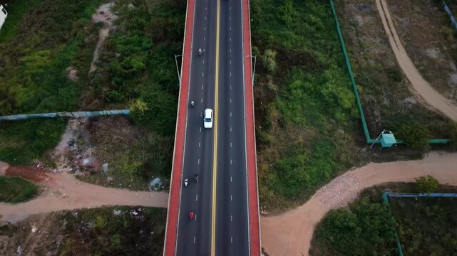 Drone top-down view of vehicles traveling along a highway surrounded by green vegetation in central Vietnam.