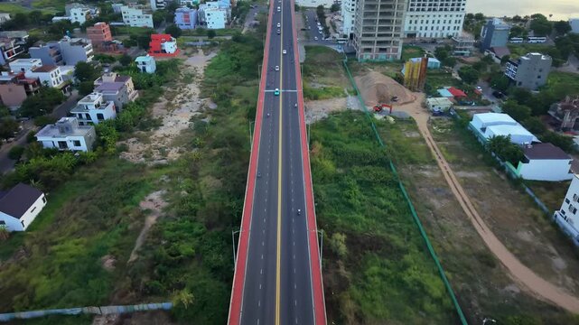 Smooth aerial drone flight over the Han River bridge with warm sunrise light illuminating the city of Da Nang, Vietnam.