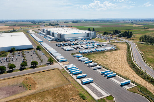 Woodburn, Oregon, USA - June 19, 2026 - Aerial drone photo of Amazon Fulfillment Center PDX8 with warehouse buildings, loading docks, trailers and logistics operations