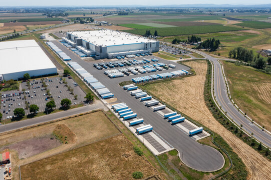 Woodburn, Oregon, USA - June 19, 2026 - Aerial drone photo of Amazon Fulfillment Center PDX8 with warehouse buildings, loading docks, trailers and logistics operations