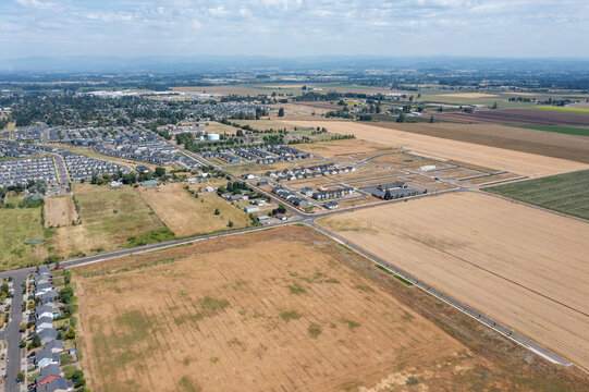Aerial drone photo of residential neighborhoods and modern apartment communities in Woodburn, Oregon, USA surrounded by farmland and suburban development near Interstate 5