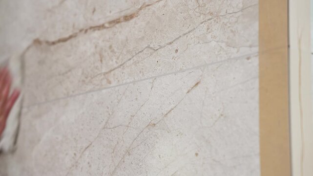 Hand polishing a marble surface with a cloth. A worker wipes down ceramic tiles after grouting them with epoxy grout.
