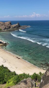  High angle view of sandy beach, ocean and rocks.