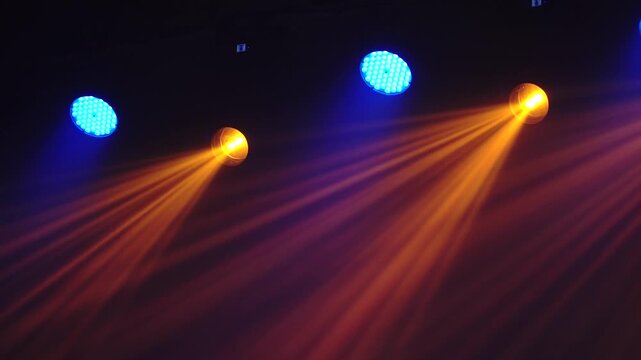 Bright theatrical spotlights shining through atmospheric haze, dynamically changing colors from crisp white to warm orange in a dark event venue.