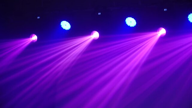 Bright theatrical spotlights shining through atmospheric haze, dynamically changing colors from crisp white to warm orange in a dark event venue.