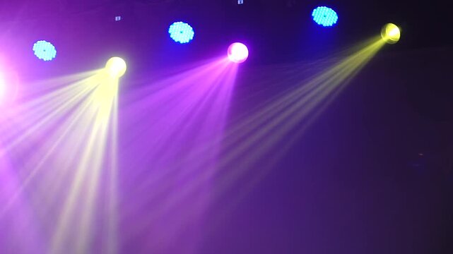 Bright theatrical spotlights shining through atmospheric haze, dynamically changing colors from crisp white to warm orange in a dark event venue.