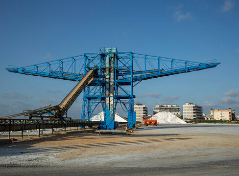 Large salt harvesting conveyor structure near salt piles and buildings in Santa Pola