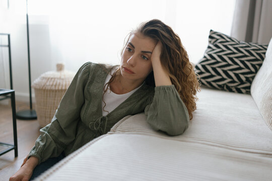 Young adult woman with depression sitting at home alone