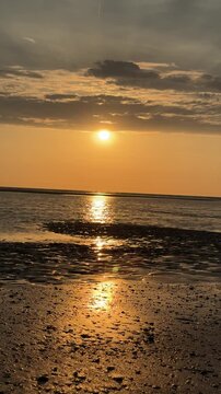 Golden sunset reflecting across wet beach at low tide