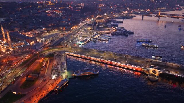 Aerial panoramic view of Golden Horn at sunset with Atat&uuml;rk Bridge, ferries, illuminated waterfront, historic Istanbul skyline, evening harbor traffic and vibrant city lights in Turkey
