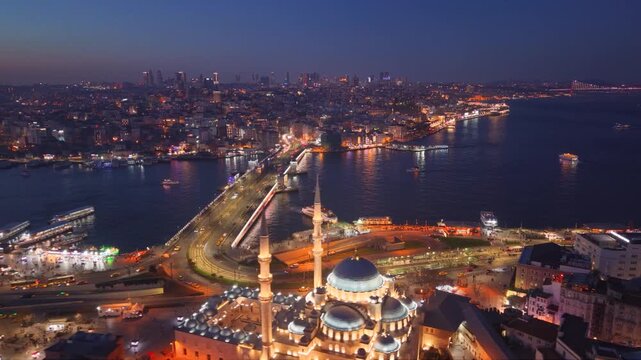Aerial twilight view of Istanbul, Turkey, overlooking the Golden Horn and Bosphorus with illuminated waterfront roads, historic mosques, dense urban neighborhoods and a suspension bridge glowing in th