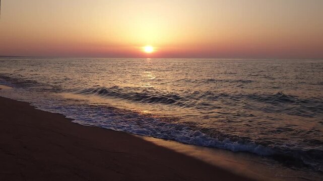 Sunset over the Sea of Japan with gentle waves on the sand beach at Hojo Sand Dunes, Tottori, Japan