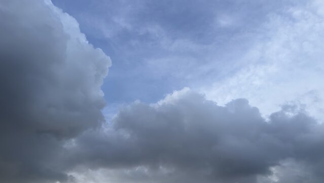 Fluffy white and grey clouds float in a bright blue sky