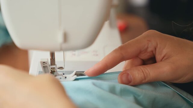 Close-up hands young woman tailor sewing clothes using sewing machine process creating dress cloth. seamstress's fabric stitching. female fashion designer process work. girl hobby home workshop space