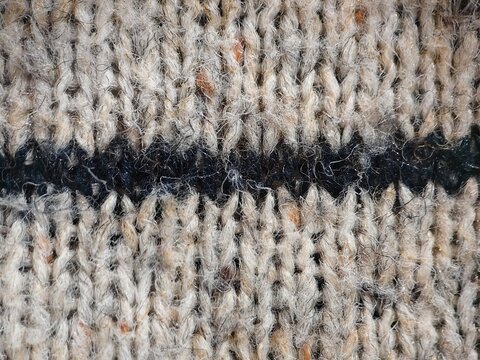 Close up striped knitted wool sweater texture with flecks, beige and black cozy fabric background