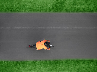 Fototapeta premium Aerial top drone high view of sporty male Cyclist with helmet shorts riding cross bicycle on black asphalt road background backdrop Top view showing man on racing bicycle riding Motion