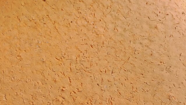 Close-up of a yellow ochre painted stucco wall featuring a grainy, textured surface with the appearance of Venetian plaster or traditional Moroccan mud wall finishes.