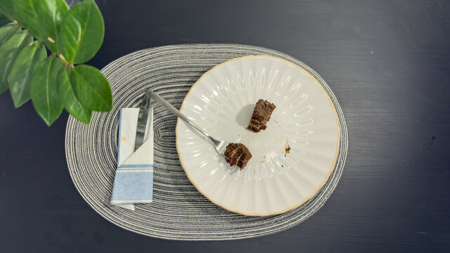 Empty dirty white plate with cake crumbs and fork after finishing dessert, top view