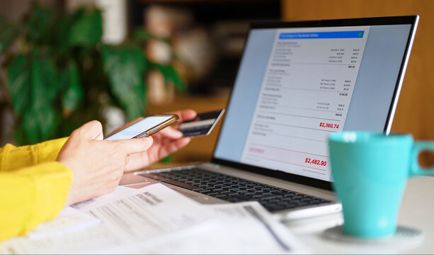 Woman calculating utility bills and household expenses on smartphone calculator.