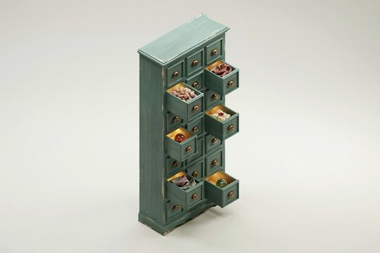 Isometric miniature bookshelf with drawers and tiny objects, green painted cabinet with cubby shelves on beige background for interior design concept
