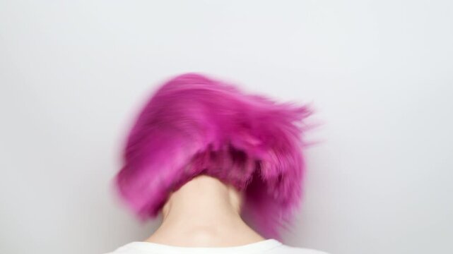 Dynamic movement of vibrant pink hair as a young woman shakes her head in studio, energetic flow and hairstyle care concept
