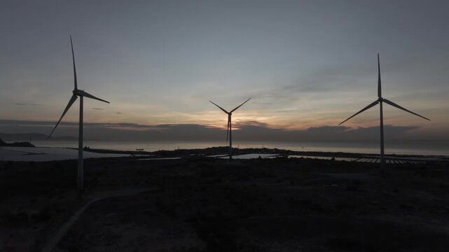 Solar panels and wind turbines in Phuoc Dinh, Khanh Hoa ( Ninh Thuan ) Vietnam. Aerial view of green energy hybrid farm, renewable power generation, and sustainable landscape.