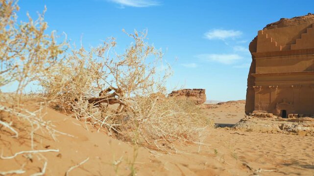 The Tomb of Lihyan - most famous tourist attraction at Hegra in Al Ula Saudi Arabia desert. Calm scene with no people, only wind moves small shrubs growing over sand