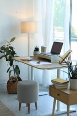 Fototapeta premium Workplace with laptop and stationery on table near window in office