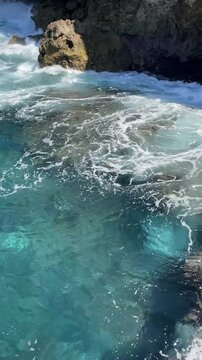 Sea waves crashing on rocky shore, high angle view.