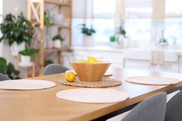 Fototapeta premium Bowl with fruits on wooden table and chairs in kitchen