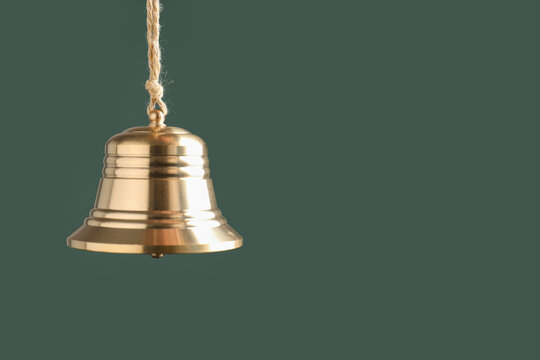 Beautiful golden bell on dark green background, closeup. Space for text