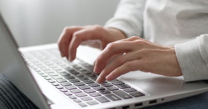 Close-up of female hands typing on a laptop keyboard during remote work or studying at home. Woman using personal computer for online communication, freelancing, or business tasks.