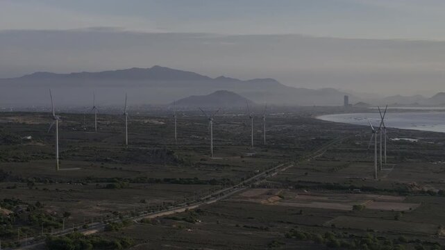 Aerial drone footage of Wind Farm in Phuoc Dinh, Khanh Hoa, Vietnam, featuring giant wind turbines along the coastal landscape, showcasing renewable energy, sustainable power and clean technology.
