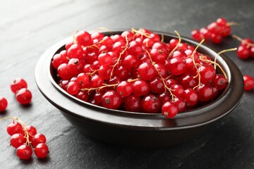 Fresh red currants in bowl on dark grey textured table, closeup © New Africa