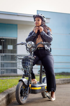 Young Black Brazilian woman fastening her helmet before riding an electric bicycle, promoting safe commuting, sustainable mobility, and eco-friendly urban transportation.