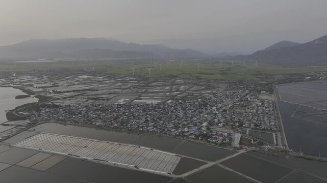Aerial drone footage of Dam Nai Wind Farm in Khanh Hoa, Vietnam, featuring rows of wind turbines across coastal wetlands, showcasing renewable energy, sustainable power and scenic landscape.