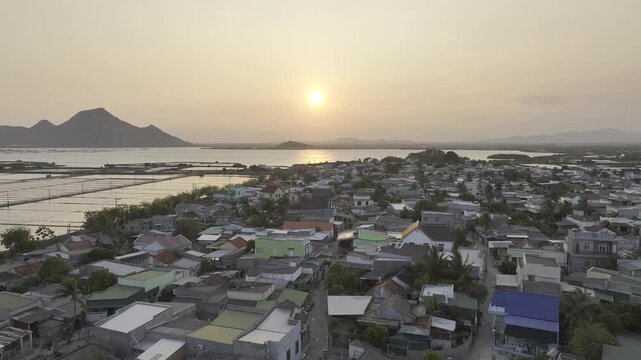 Aerial drone footage of sunset over Dam Nai Lagoon, Khanh Hoa, Vietnam, featuring golden reflections, tranquil waters, fishing boats and breathtaking coastal landscape at golden hour.