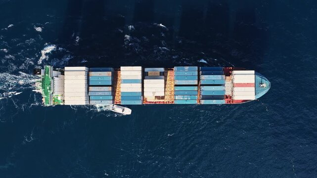 Shipping logistics. Commercial shipping. Cargo ship at sea, aerial top view. Freight container loaded on cargo tanker. Aerial cargo ship passing harbor. Cargo business. Container ship
