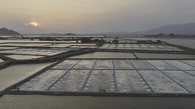 Aerial drone footage of Phuong Cuu Salt Fields in Khanh Hoa, Vietnam, showcasing traditional sea salt production, geometric salt ponds, coastal landscape and sustainable local industry.