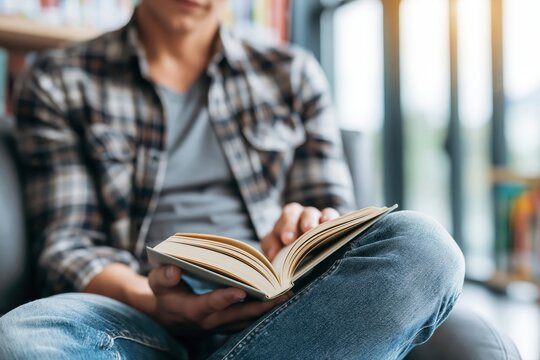 Young man reading a book while sitting comfortably on a cozy sofa