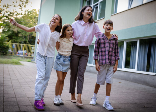 Group of children and teacher smiling outside school