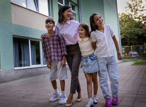 Group of children and teacher smiling outside school