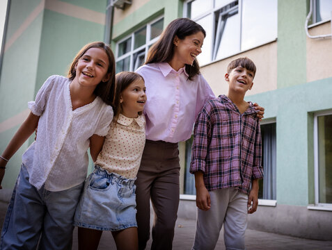 Group of children and teacher smiling outside school