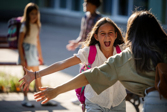 Mother greets daughter in schoolyard